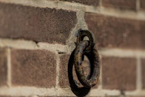 Detailopname van een historische ijzeren teugelring bevestigd aan een oude buitenmuur op de kazerne.
